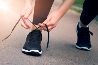 Sabah koşusu. Gün batımında siyah spor ayakkabılarla kırsal bir yolda koşan genç bir bayan. Koşmadan önce ayakkabı bağcıklarını bağlayan kız