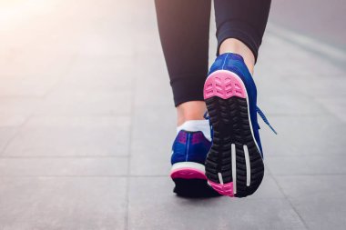 Sabah koşusu. Kırsal bir yolda koşan genç bayan gün batımında siyah tabanlı mavi spor ayakkabılarla koşuyor. Sağlıklı bir yaşam tarzı. Spor eğitimi konsepti