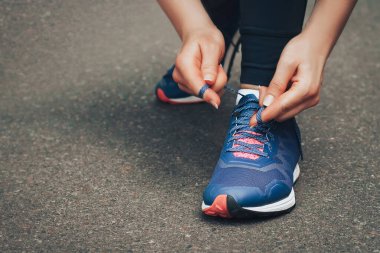 Akşam koşusu. Kırsal bir yolda mavi spor ayakkabılarla günbatımında koşan genç bir bayan. Koşmadan önce ayakkabı bağcıklarını bağlayan kız