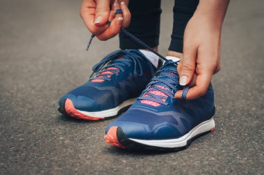 Akşam koşusu. Kırsal bir yolda mavi spor ayakkabılarla günbatımında koşan genç bir bayan. Koşmadan önce ayakkabı bağcıklarını bağlayan kız