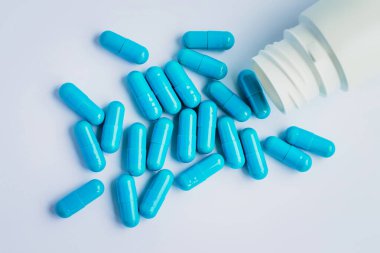 Mavi kapsüller, açık mavi arka planda haplar. Kapsüller beyaz teneke kutuda. Vitaminler, kadın sağlığı için besin takviyeleri