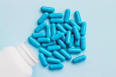 Mavi kapsüller, açık mavi arka planda haplar. Kapsüller beyaz teneke kutuda. Vitaminler, kadın sağlığı için besin takviyeleri