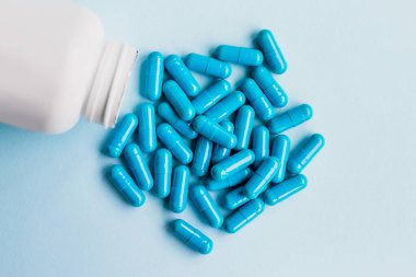 Mavi kapsüller, açık mavi arka planda haplar. Kapsüller beyaz teneke kutuda. Vitaminler, kadın sağlığı için besin takviyeleri
