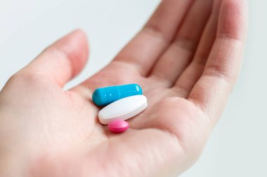 Beyaz arka planda kadın avucunda mavi ve beyaz hap kapsülü var. Kadın elinde antidepresan haplar. Avucunun içinde hap tutan bir kadın.