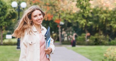Parkta sevinçten zıplayan sarışın kız öğrenci. Kız sınavı başarıyla geçti, eğitim konsepti, kopya alanı