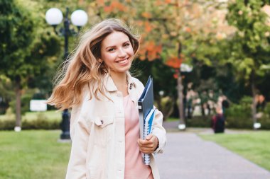 Parkta sevinçten zıplayan sarışın kız öğrenci. Kız sınavı başarıyla geçti, eğitim konsepti, kopya alanı