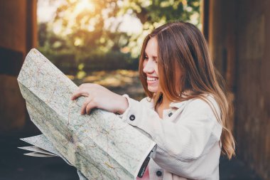 Sarışın kız haritaya bakıyor. Kız öğrenci şehirde kayboldu ve bir yol arıyor.