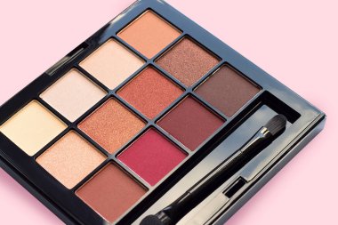 Pembe arka planda kahverengi tonlarda, mat ve ışıltılı göz farları, yakın plan. Sonbahar göz farı paleti, kadın dekoratif kozmetik ürünleri