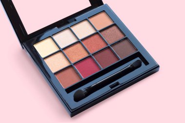 Pembe arka planda kahverengi tonlarda, mat ve ışıltılı göz farları, yakın plan. Sonbahar göz farı paleti, kadın dekoratif kozmetik ürünleri