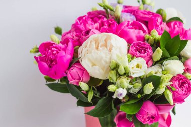 Şapka kutusunda çiçek aranjmanı. Şakayık buketi, coşku, pembe bir kutuda gül, beyaz bir arka planda vaha.