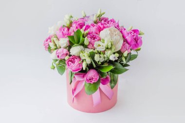 Şapka kutusunda çiçek aranjmanı. Şakayık buketi, coşku, pembe bir kutuda gül, beyaz bir arka planda vaha.