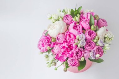 Şapka kutusunda çiçek aranjmanı. Şakayık buketi, coşku, pembe bir kutuda gül, beyaz bir arka planda vaha.