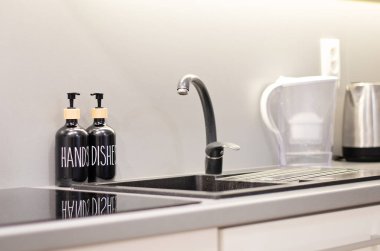 Siyah ve gri mutfak, soba ve lavabo içine inşa edilmiş. Temiz mutfak çalışma alanı.