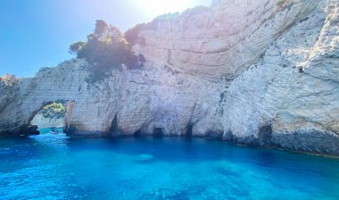 Yunanistan 'ın Zakynthos kentindeki Mavi Mağaraların Kaya Kemerleri. Güneşli bir günde, İyon Denizi 'nin mavi sularında turistlerle birlikte turistik bir teknenin manzarası. Turist eğlencesi.