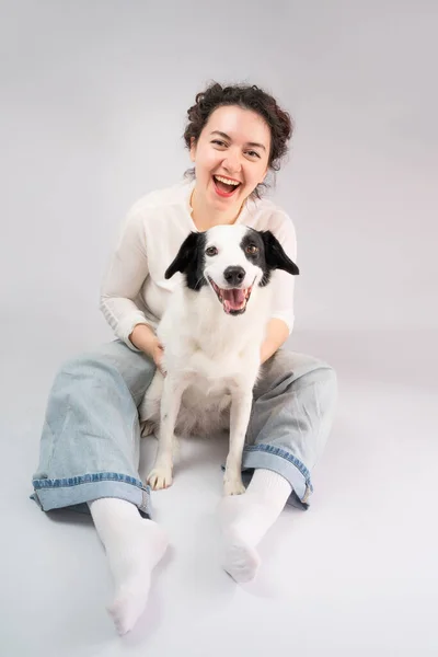 Szczęśliwa Śmiejąca Się Kobieta Jej Pies Patrzący Kamerę Siedzącą Szarej — Zdjęcie stockowe