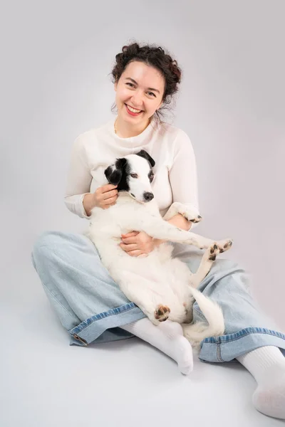 Szczęśliwa Kobieta Przytulająca Białego Psa Siedzącego Szarym Tle Najlepsza Chwila — Zdjęcie stockowe