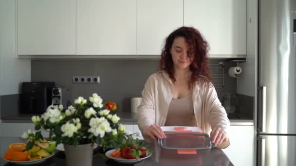 Kręcone Włosy Piękna Młoda Kobieta Kuchni Trzymając Różowy Pudełko Lunch — Wideo stockowe
