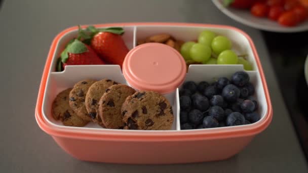 Aan Tafel Roze Plastic Lunchbox Met Koekjes Amandel Bosbessen Aardbeien — Stockvideo