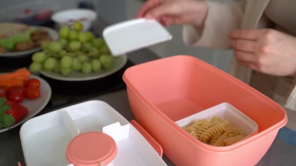 准备在外面吃饭的午餐带去 女人的手放在饭盒里 意大利面和三明治 粉红塑料食品容器 早上在厨房里准备好 — 图库视频影像