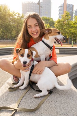 Kameraya bakan genç köpek Jack Russell 'a sarılıp sarmaş dolaş. Yaz tatili havası. Parlak turuncu renkli giysiler. Sevgi ve güven sahibi kameraya bakıyor.