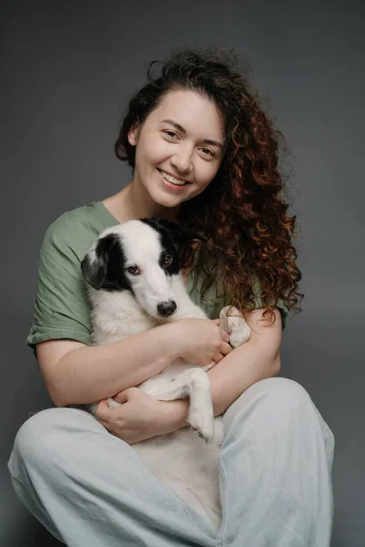 Woman and dog hug. Lovely friends portrait looking at the camera. border collie pet cuddling with smiling curly haired owner woman in blue jeans. Vertical composition