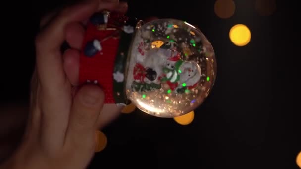グラスボールのおもちゃ 冬の伝統的な雪のシンボル クリスマスのシンボルクリスタルの雪の地球を握る女性の手 スローモーション垂直リールビデオ映像 ハンドホールドカメラ — ストック動画