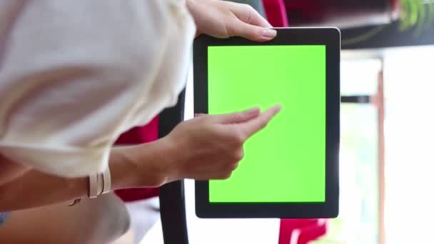 拿着带有绿色铬屏的移动平板电脑的妇女 竖起大拇指 带有红色椅子的咖啡馆中的垂直视频镜头 — 图库视频影像