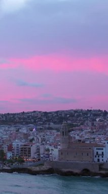 İspanya Katalonya 'da güzel bir günbatımı. Mor ve pembe büyüleyici gerçek dışı renklerdir. İnsansız hava aracından deniz manzarası. Dikey video görüntüleri