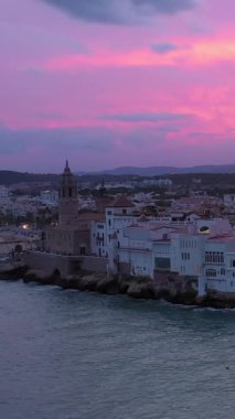Sitges Katalonya İspanya günbatımı şehri. Mor ve pembe büyüleyici gerçek dışı renklerdir. İnsansız hava aracından deniz manzarası. Dikey video görüntüleri