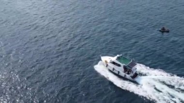 Bir motorlu tekne mavi denizde yelken açar. İnsansız hava aracının görüntüsü