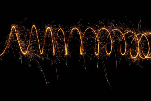 黒い背景に火花を散らす螺旋状の光 長い露出のクリスマスライト — ストック写真