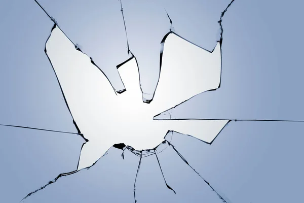 Stock image Broken glass on a blue background. Photo of a broken window with cracks and a white light in the center