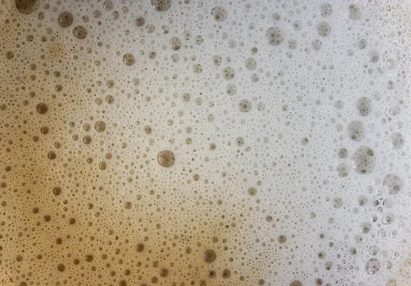 Coffee foam with milk close-up. Fresh coffee, morning drink, background cream with bubbles. Cappuccino or latte