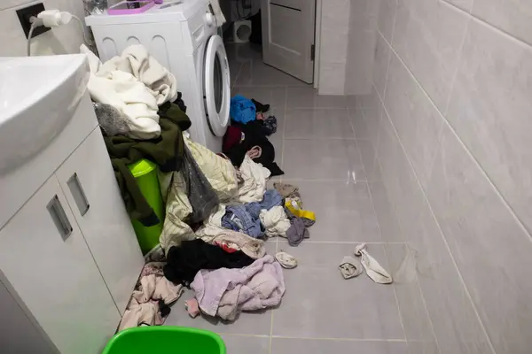 Dirty clothes are scattered near the washing machine