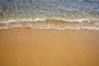 Kumsalda şeffaf bir su dalgası. Kuma yakın çekim.