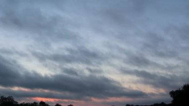 Renkli bir gün doğumunun üzerinden geçen dramatik bulutların zaman çizelgesini yakalamak değişen ışık ve gölgelerle nefes kesici bir atmosfer manzarası yaratır.