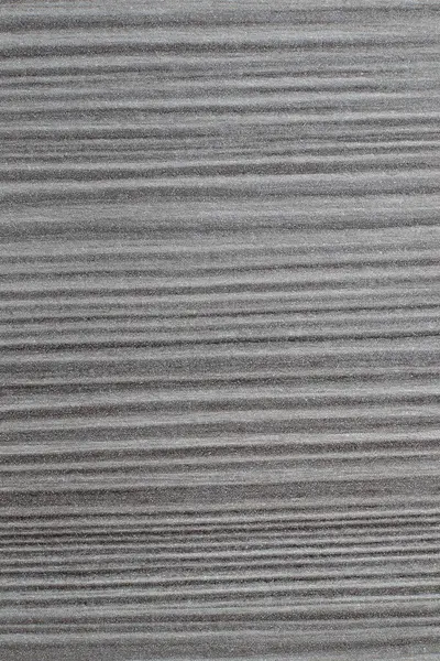 Koyu gri, ahşap bir yüzeyi yakından görmek ince ve paralel çizgilerin ayırt edici bir modelini içerir.