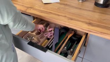 Kadın mutfak çekmecesini düzenlemek için çatal bıçak takımını düzenliyor.