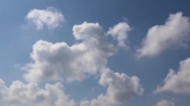 Güzel beyaz bulutlar açık mavi gökyüzünde yavaşça hareket ediyor.