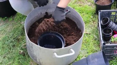 Bahçıvan çiçek dikmek için saksı toprağı hazırlıyor.