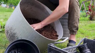 Bahçıvan çiçek dikmek için saksı toprağı hazırlıyor.
