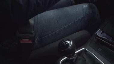 Kadınların elleri mekanik şanzıman değiştiriyor. Tarafsız vites. Kırmızı manikürlü tırnaklar, yüzük parmağı. Yakın plan. Emniyet kemeri, maske, telefon, anahtar, kot pantolon, ceket arka planı. El kamerasıyla ateş edilmiş. Yaz, bahar