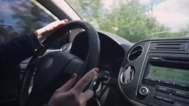 Yakın çekim hareket halinde. Kadın elleri eski bir direksiyonu tutar ve araba kullanır, kırmızı bir manikür görünür, bir alyans. jestler