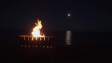 Bir şenlik ateşi, Brezilya 'da bir alev, denizin arka planında, okyanusta, mehtaplı bir yolda. Harika bir gece. Güzel arka plan. tripod kamera