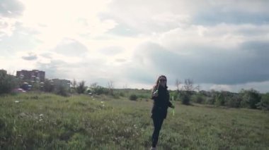 Güzel bir genç kız sokakta, doğada sabun köpükleri üflerken seviniyor. Güneşin altında eğlenmek. Rüzgâr kabarcıklar çıkarıyor. Gün doğumu. Baloncuklara odaklan.