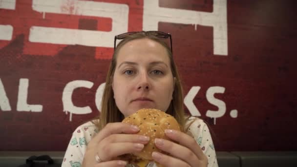 Młoda Głodna Ciężarna Kobieta Chciwie Jedząca Hamburgera Restauracji Szybkiej Obsługi — Wideo stockowe