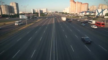 Sekiz şeritli asfalt yolda trafik, arabalar, kamyonlar, otobüsler. Trafik sıkışıklığı, trafik sıkışıklığı, yerleşim yerlerinde trafik vardı. Otoparklar, dükkanlar, benzin istasyonları, yüksek binalar