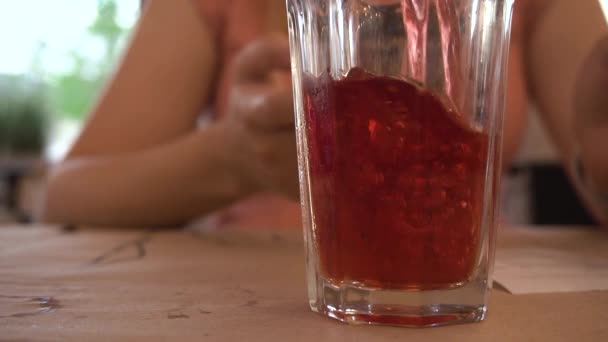 接近中だ 赤いコンポートは街のカフェの透明なガラスに注がれ 女の子の背景を背景にしている 液体泡だ スローモーション — ストック動画