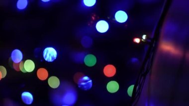 Gece karanlığında, bir Noel ağacının üzerinde, bir çelenk gibi bulanık bir çelenk. Noel tatili, Noel süslemeleri, balolar için yanıp sönen ampuller. Çeviriyi Odakla