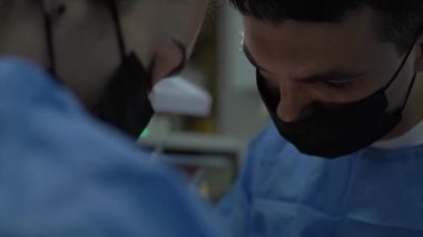Diş cerrahlarından oluşan bir ekip dişlerini ameliyat eder. Modern bir klinikte. Genç dişçi. Takım çalışması. Diş doktoru ortodontist cerrah kanal tedavisi yapıyor. Stomatoloji Ofisi